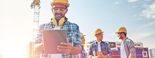 Baufachkraft mit Helm und Tablet auf einer Baustelle